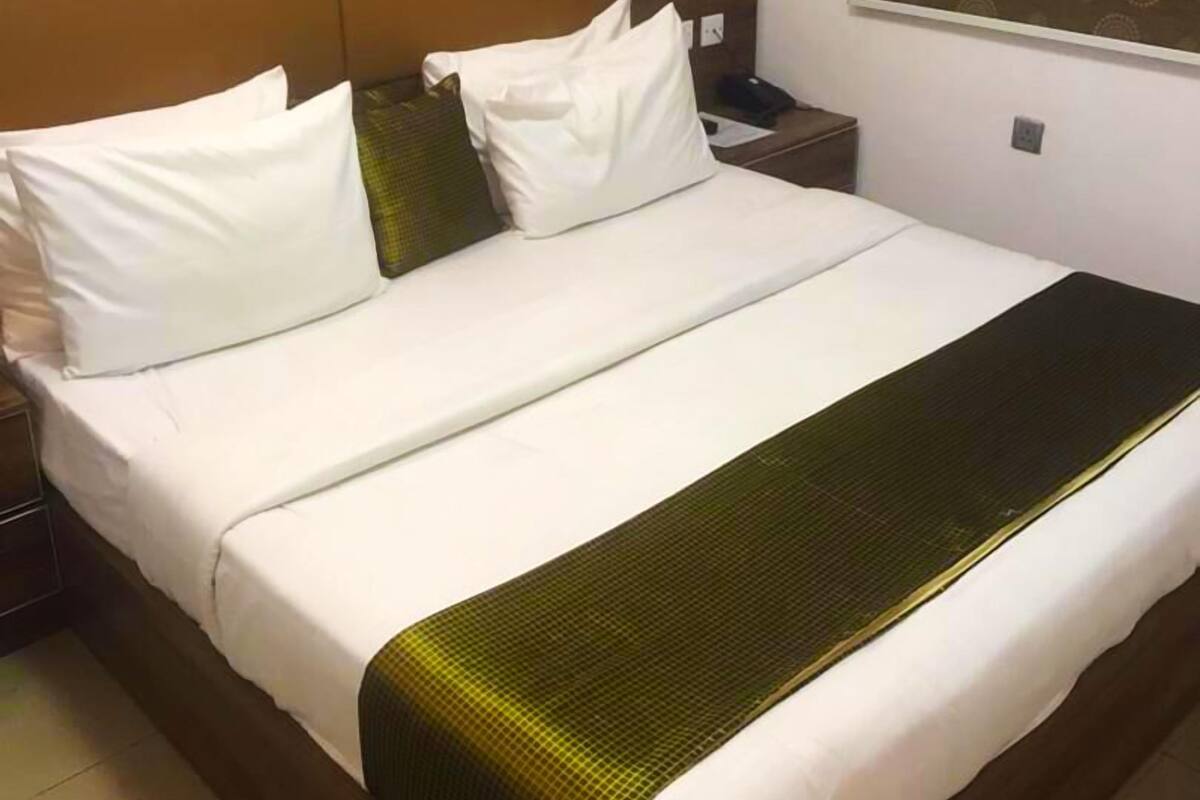 A hotel room with a large bed, a nightstand, a telephone, and a colorful abstract painting on the wall.