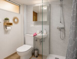 A modern bathroom with a toilet, sink, and shower.