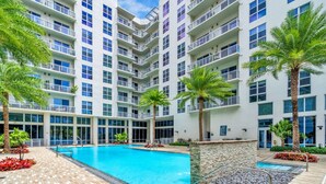 A multi-story hotel with a central swimming pool, balconies, and palm trees. - Comfort & Convenience: 2BR Unit with Free Parking! (Miami)