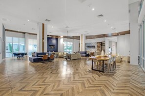 A spacious lobby with a herringbone wood floor, a central seating area with sofas and chairs, and large windows providing natural light. - Comfort & Convenience: 2BR Unit with Free Parking! (Miami)