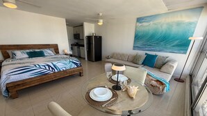 Une chambre d’hôtel moderne comprenant un lit, une table à manger avec des chaises, un canapé et une grande fenêtre.