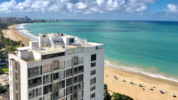 Un hôtel de grande hauteur doté de nombreux balcons offrant une vue sur une plage et l’océan.
