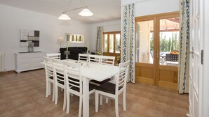 A dining area with a white table and chairs, a black sofa, and a chandelier. - Finca Carlotta with pool, garden, A/C in the bedrooms, Wifi, beach approx. 4 km (IB)