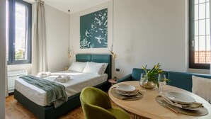 A modern bedroom with a bed, bedside table, and a dining area with chairs and a table. - Cozy and Central Studio in Bovisa, Milan (Milan)