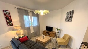 A living room with a sofa, a coffee table, a TV, a chair, and a lamp. - Apartment in Carantec Near Sandy Beaches (Carantec)