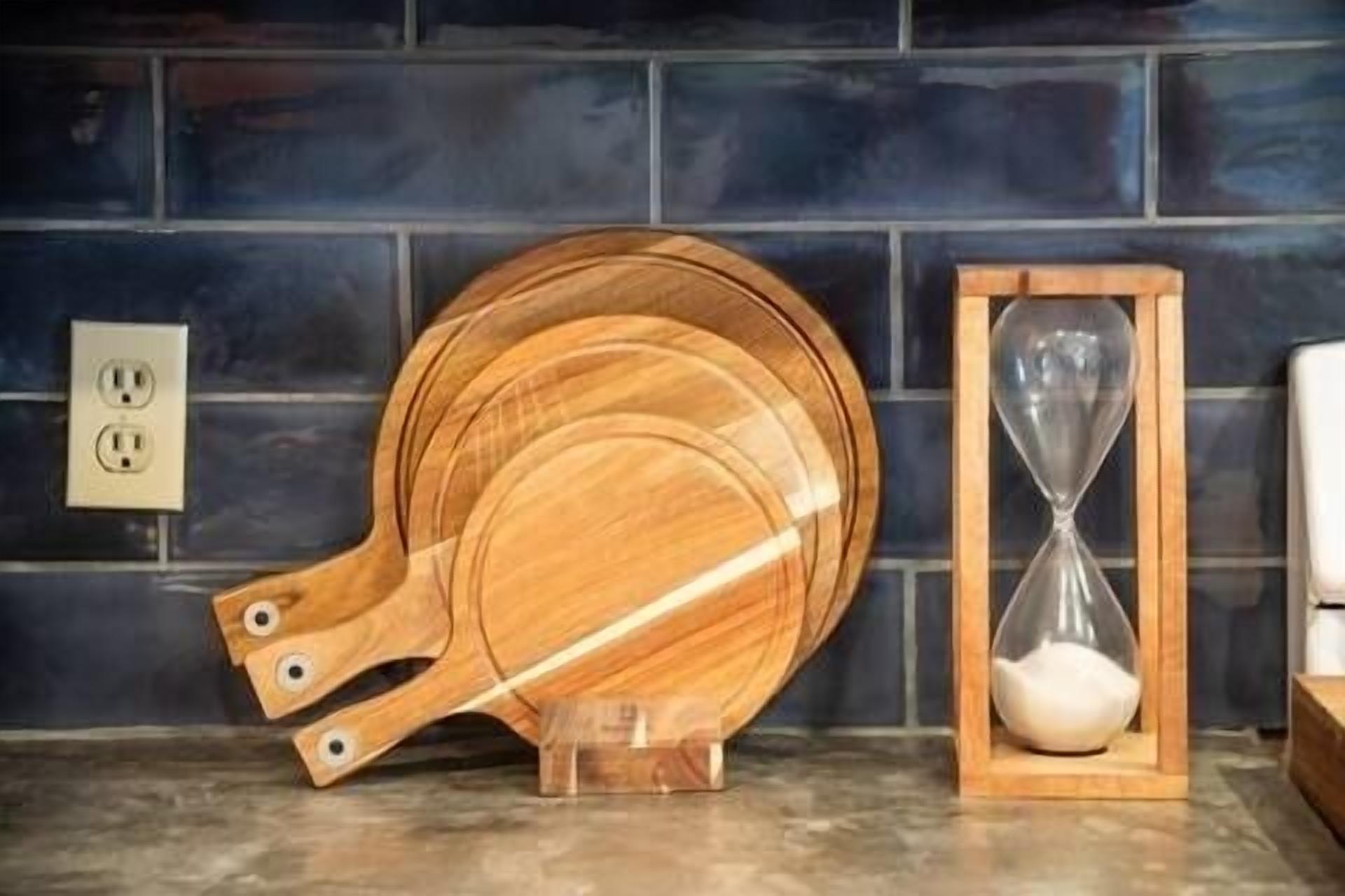 A kitchen counter with wooden cutting boards and an hourglass.
