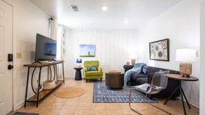 A modern living room with a television, a green armchair, a black sofa, and a coffee table. - The Ace, 1BR King Duplex by Velvet Ditch Villas (Oxford)