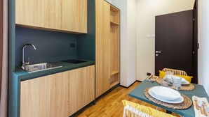Une cuisine compacte avec des meubles en bois, un évier et un coin repas avec une table dressée pour deux personnes.
