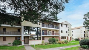 A multi-story residential building with balconies, a central courtyard, and surrounding greenery. - T2 cosy - Vue Golf - Proche Plage (Pornic)