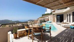 Eine Dachterrasse mit Pool, Sitzgelegenheiten im Freien und Blick auf die Landschaft.