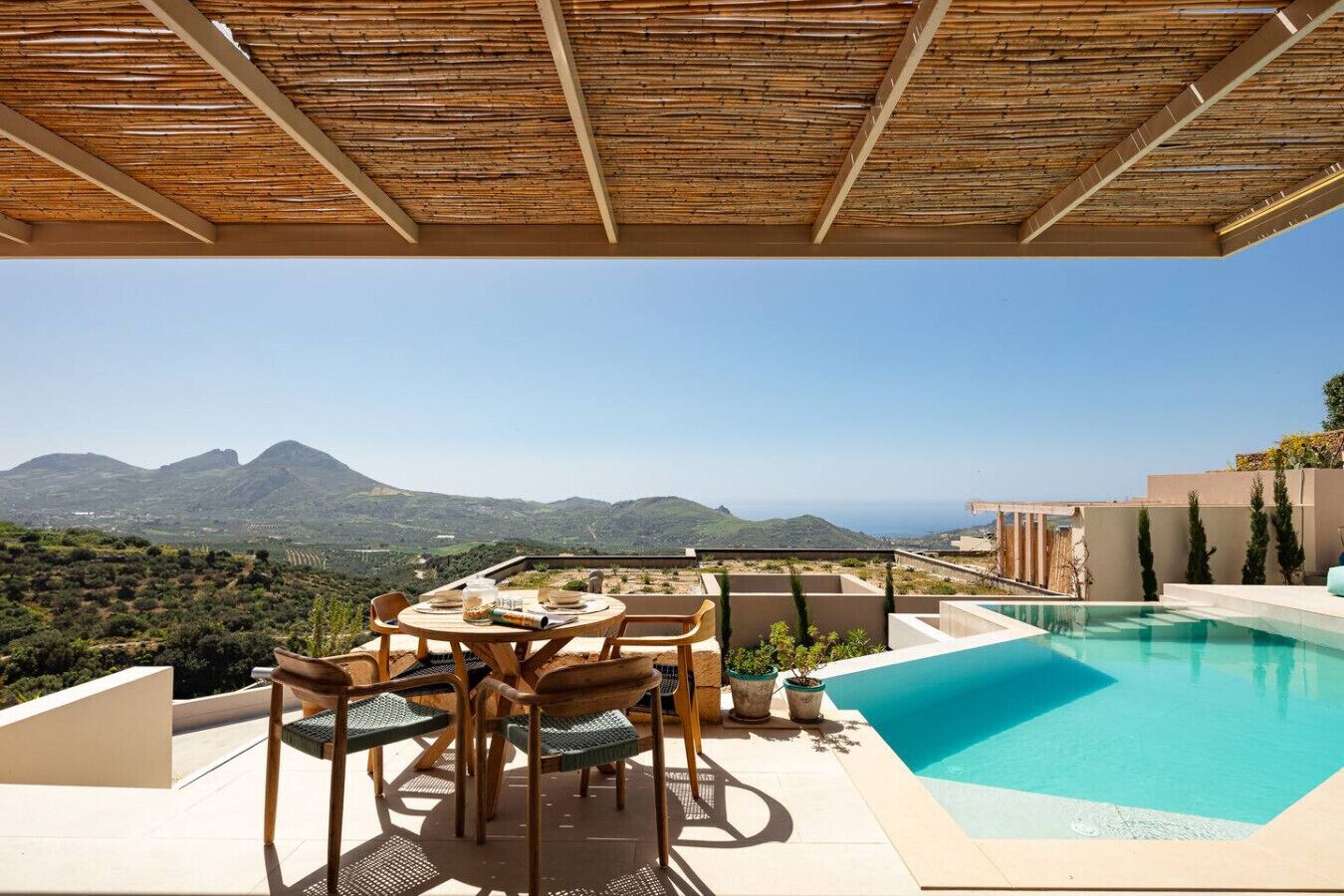 A rooftop terrace with a pool, dining area, and a view of mountains.