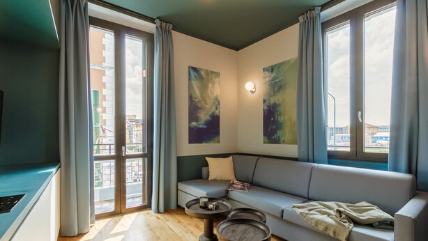 Een moderne woonkamer met een grijze bank, twee ronde bijzettafels en abstracte wanddecoratie.