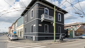 Een gebouw met twee verdiepingen, een balkon op de tweede etage, een bord met daarop 'hotel' en een geparkeerde scooter.