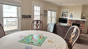 Una sala de estar acogedora con una mesa redonda lista para juegos de mesa, una chimenea y un televisor.