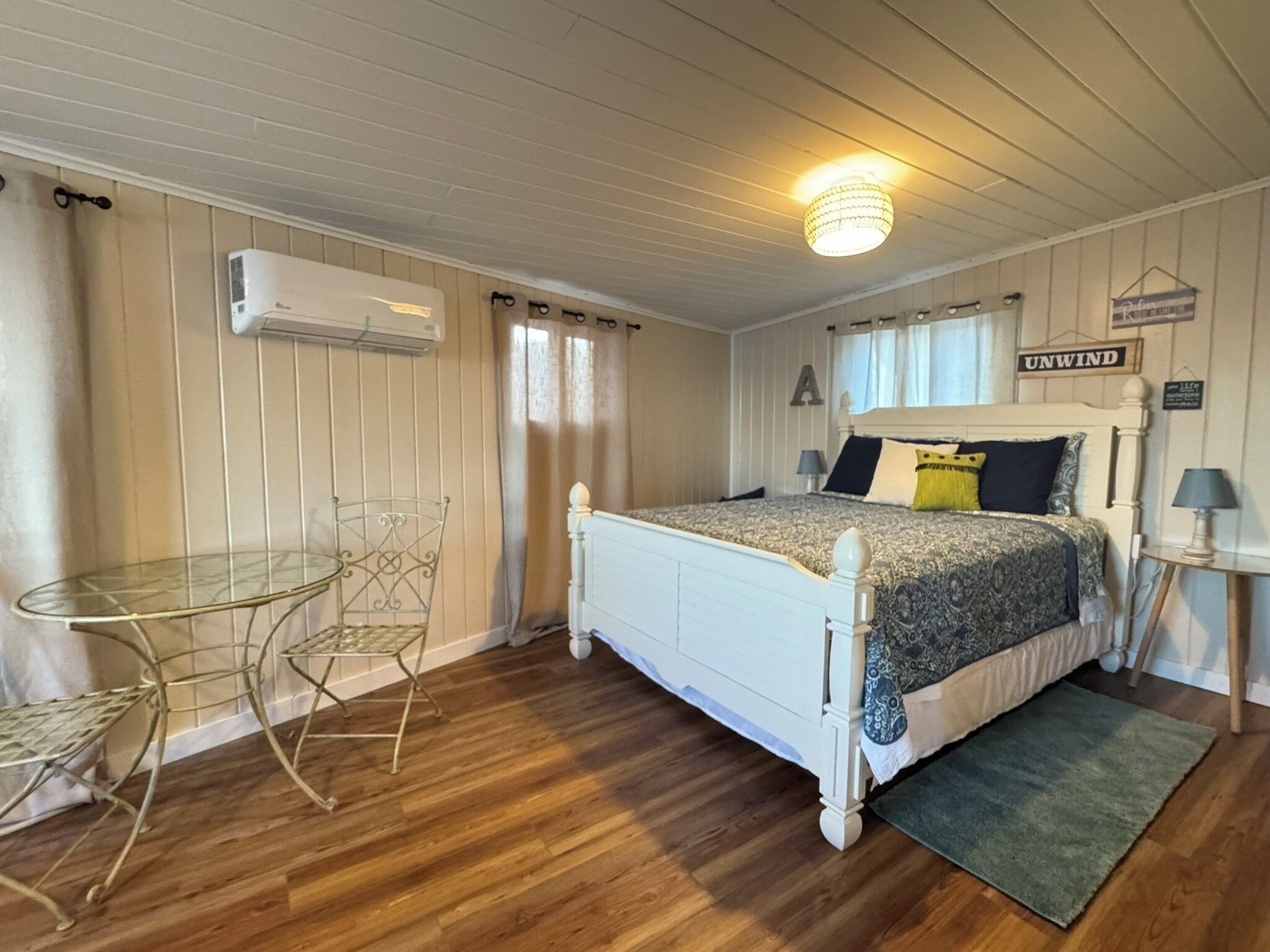 A bedroom with a bed, a small table, and a chair.