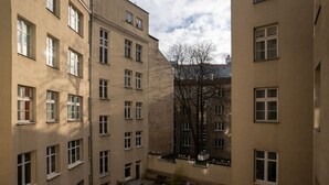 Un immeuble à plusieurs étages doté d’une cour intérieure aménagée avec des espaces de repos en plein air et un arbre.