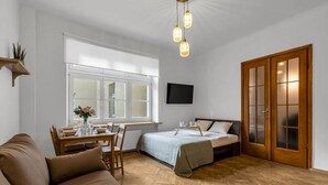 Une chambre à coucher avec un lit, un bureau, une chaise, un canapé, une télévision et une fenêtre.