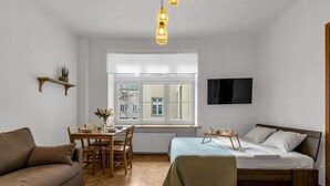 Une pièce de taille modeste comprenant un lit, un canapé, une table à manger avec des chaises, une fenêtre donnant sur un paysage agréable et un téléviseur fixé au mur.
