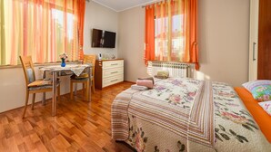 Une chambre à coucher avec un lit, un bureau et une chaise, un radiateur et un téléviseur fixé au mur.
