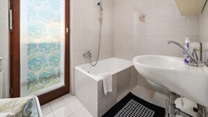 Une salle de bain avec une douche, une baignoire et un lavabo.