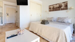 A bedroom with a bed, a TV mounted on the wall, a painting above the bed, and a lamp on the nightstand. - Studio in Marbella Near Romana Playa Beach (Marbella)