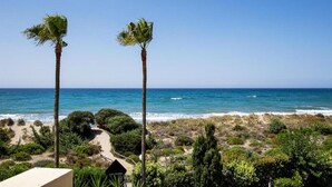 A coastal landscape with two palm trees, a sandy beach, and a clear view of the ocean. - Studio in Marbella Near Romana Playa Beach (Marbella)