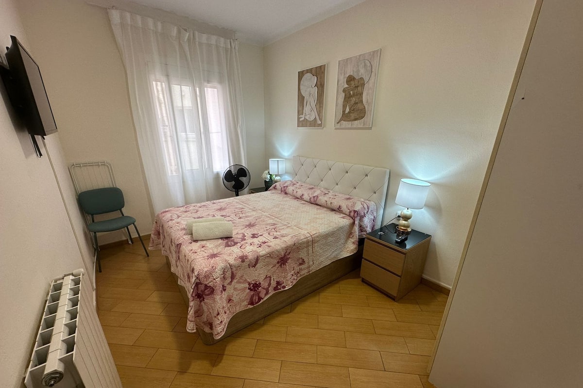 Une chambre à coucher comprenant un lit, une chaise, une table de chevet avec une lampe et un radiateur.