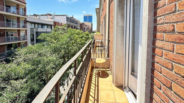 A balcony with a view of neighboring buildings and dense foliage. - Rooms Valencia (Barcelona)