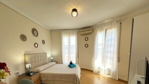A hotel room with a bed, a desk, a chair, a TV, and a window with curtains. - Rooms Valencia (Barcelona)