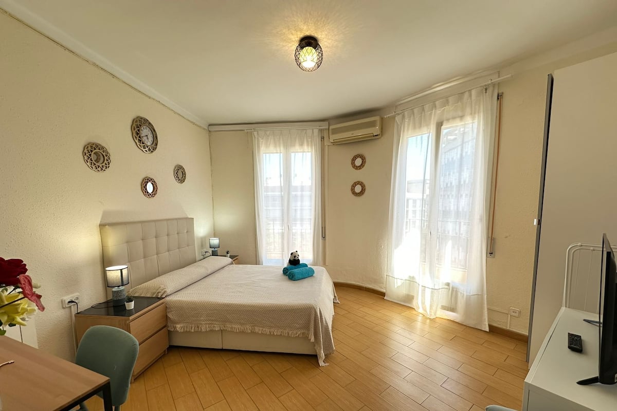 Une chambre d’hôtel équipée d’un lit, d’un bureau, d’une chaise, d’une télévision et d’une fenêtre avec des rideaux.