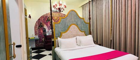 A hotel room with a checkered floor, a bed with white and pink bedding, a chandelier, and a curtain on the window.