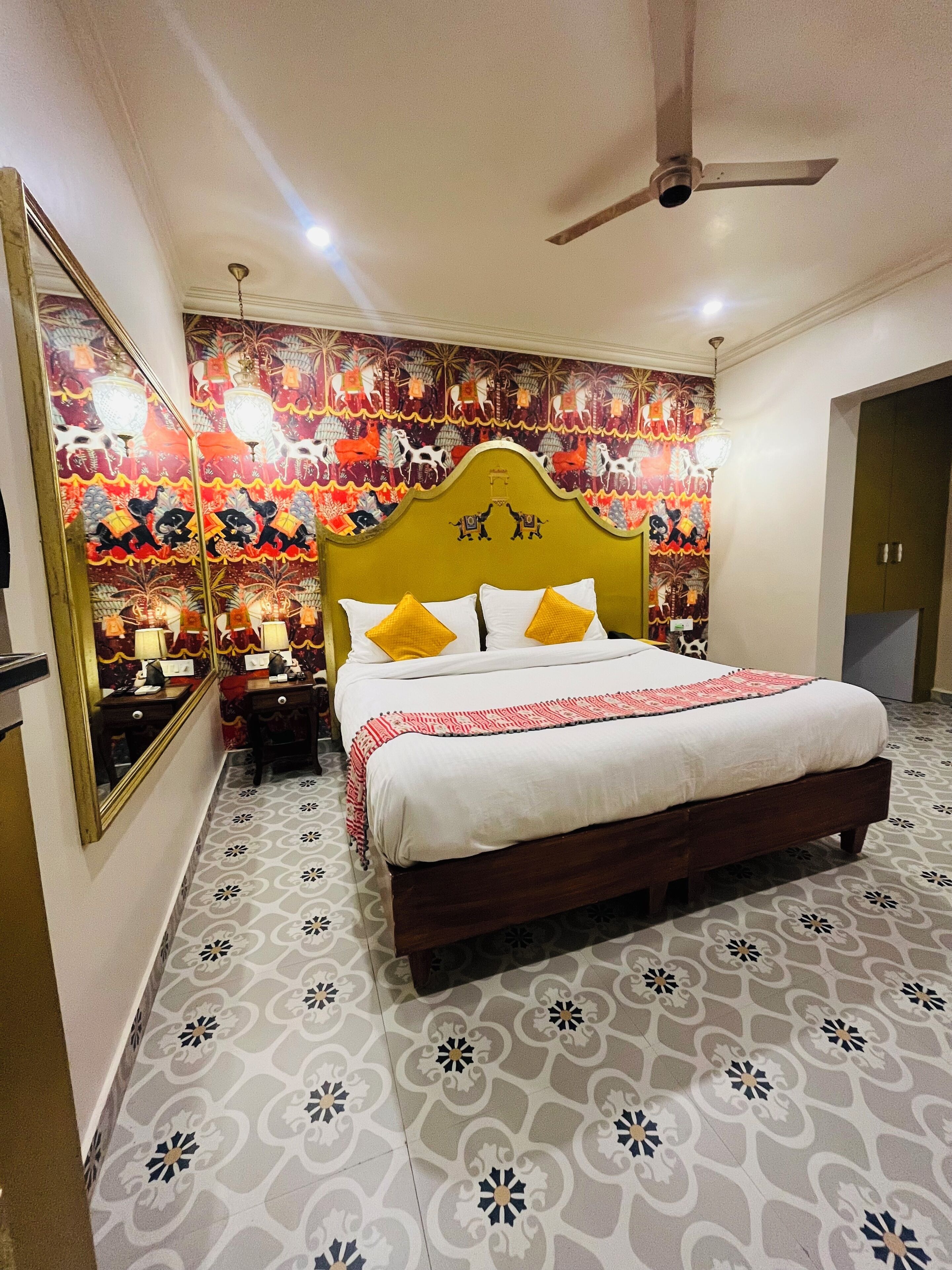 Une chambre à coucher avec un grand lit, une tête de lit ornée de motifs décoratifs, une table de chevet et un miroir.