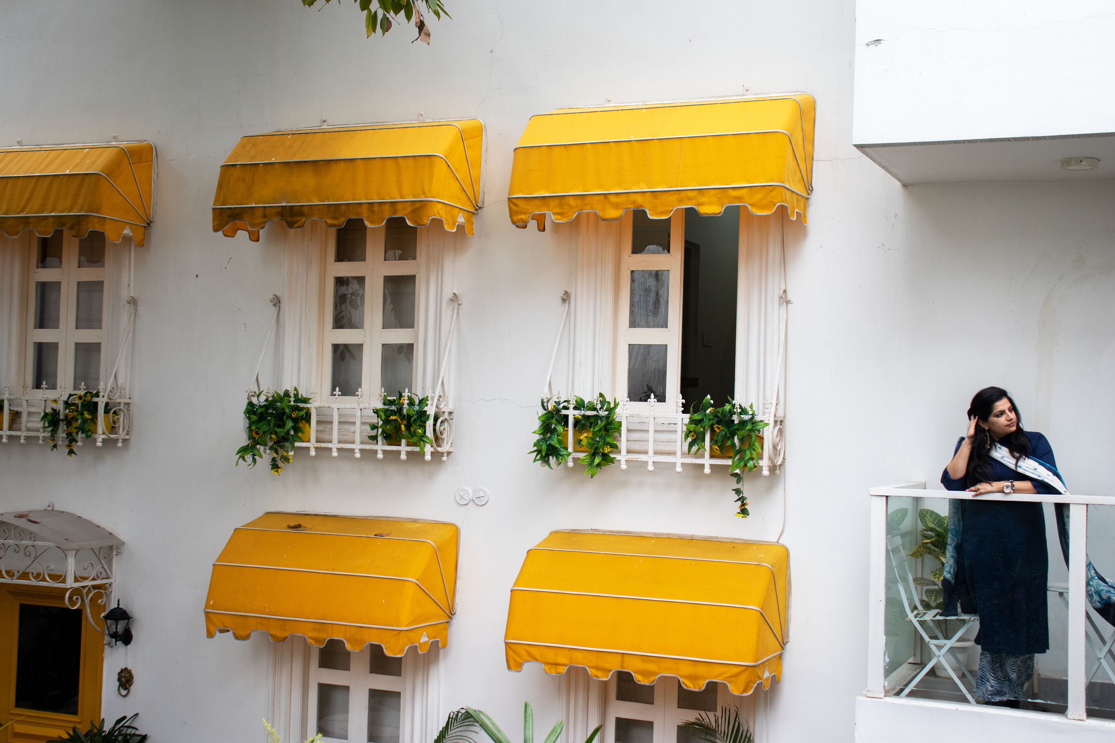 A building facade with multiple windows, each with a yellow awning and white shutters.
