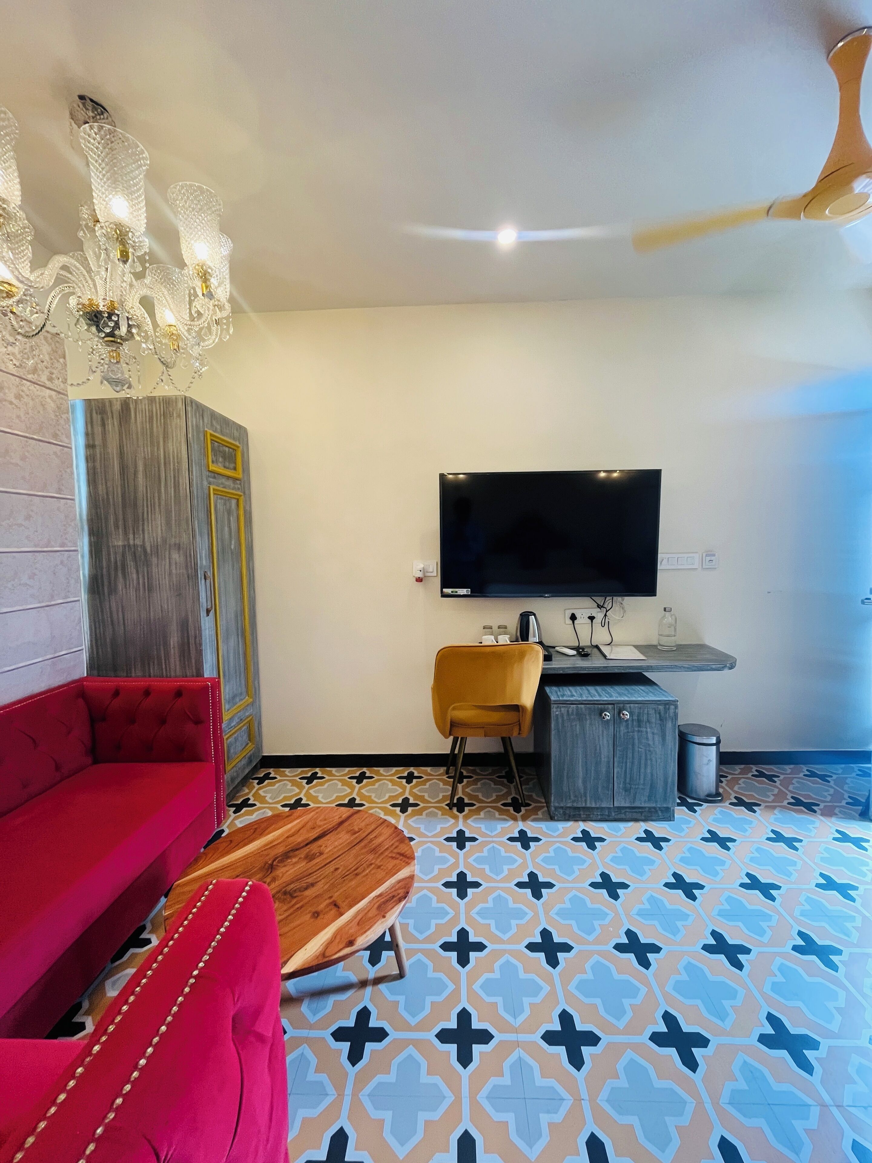 A modern living room with a red sofa, a yellow chair, a wooden coffee table, a TV, and a patterned floor.