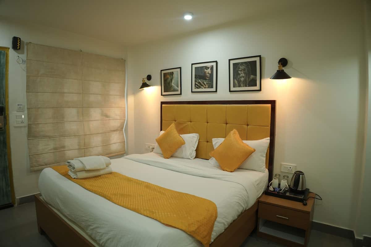 A hotel room with a bed, a nightstand, a lamp, and framed pictures on the wall.