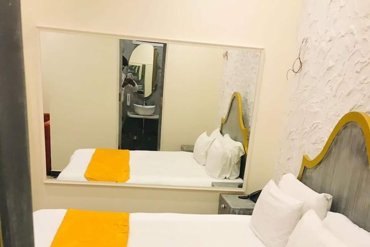 A hotel room with a bed, a mirror, and a wall with a textured pattern.
