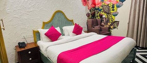 A bedroom with a bed, nightstand, and a wall mural.