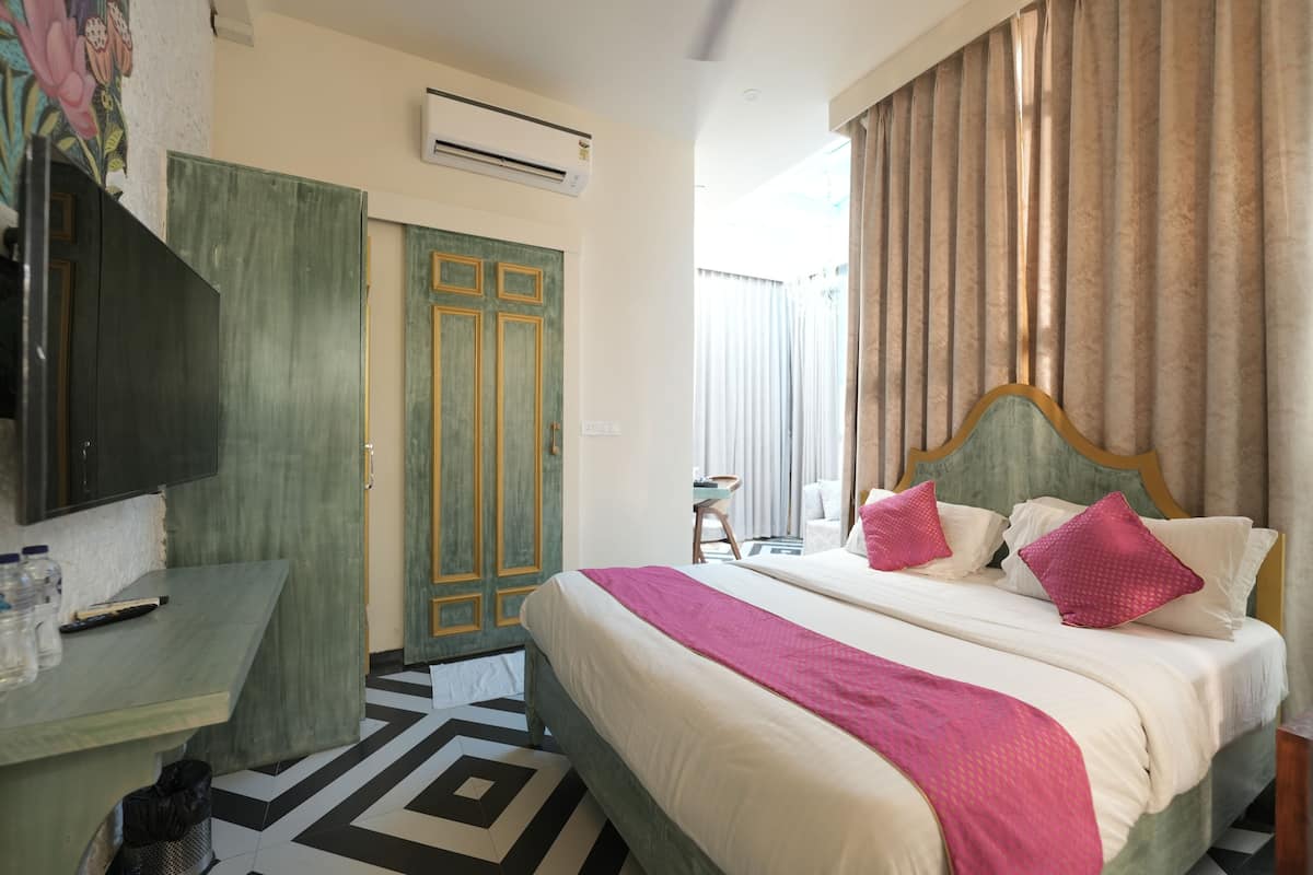 A hotel room with a bed, a desk, a chair, and a window with curtains.
