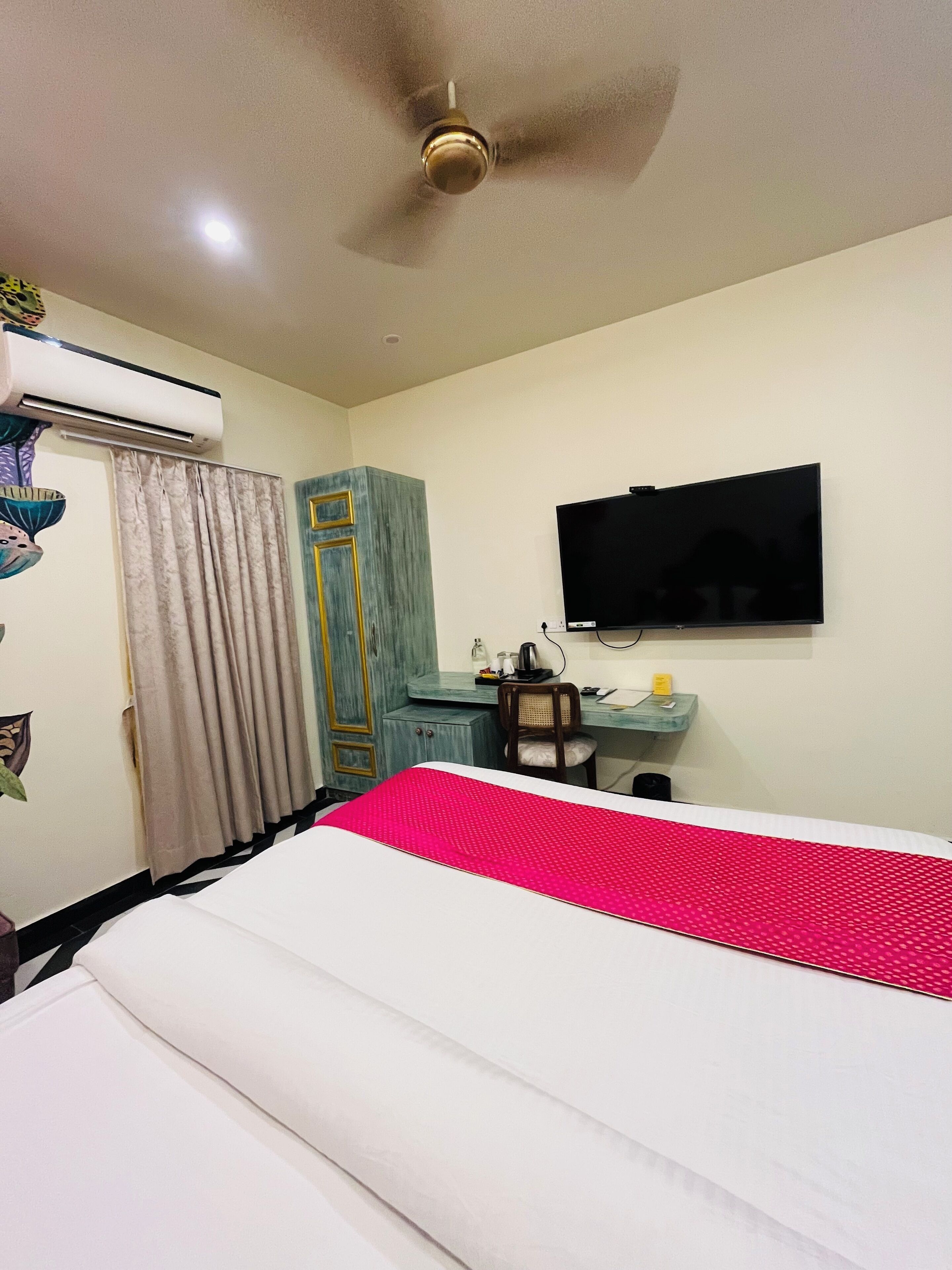 Une chambre d’hôtel équipée d’un lit, d’un bureau, d’une chaise, d’une télévision et d’un appareil de climatisation.