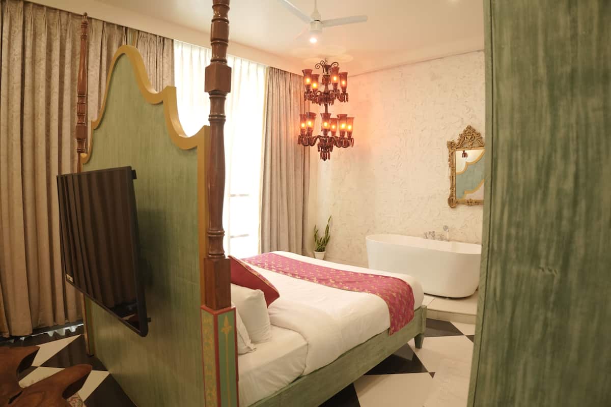 A bedroom with a four-poster bed, a chandelier, a bathtub, and a mirror on the wall.
