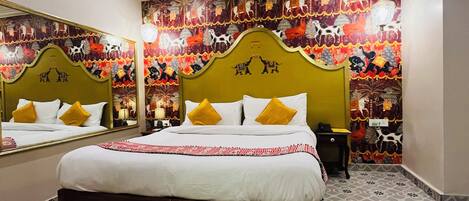 A hotel room with a large bed, a ceiling fan, patterned floor tiles, and a vibrant wall mural.