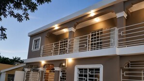 A two-story building with a balcony, a garage, and a utility box.