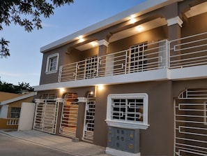 A two-story building with a balcony, a garage, and a utility box.
