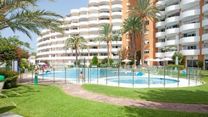 A hotel with multiple balconies, a swimming pool, and palm trees. - House in Marbella Near Sandy Beach (Marbella)