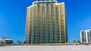 A high-rise hotel with a modern design, featuring multiple balconies and a beachside location.