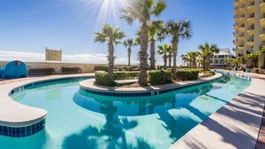 A swimming pool with a curved design, surrounded by palm trees and a tall building in the background.