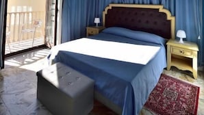 Un dormitorio con una cama, una mesita de noche, una lámpara, una ventana con cortinas y una alfombra roja.