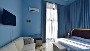 Una habitación de hotel con cama, sofá, escritorio y televisor.