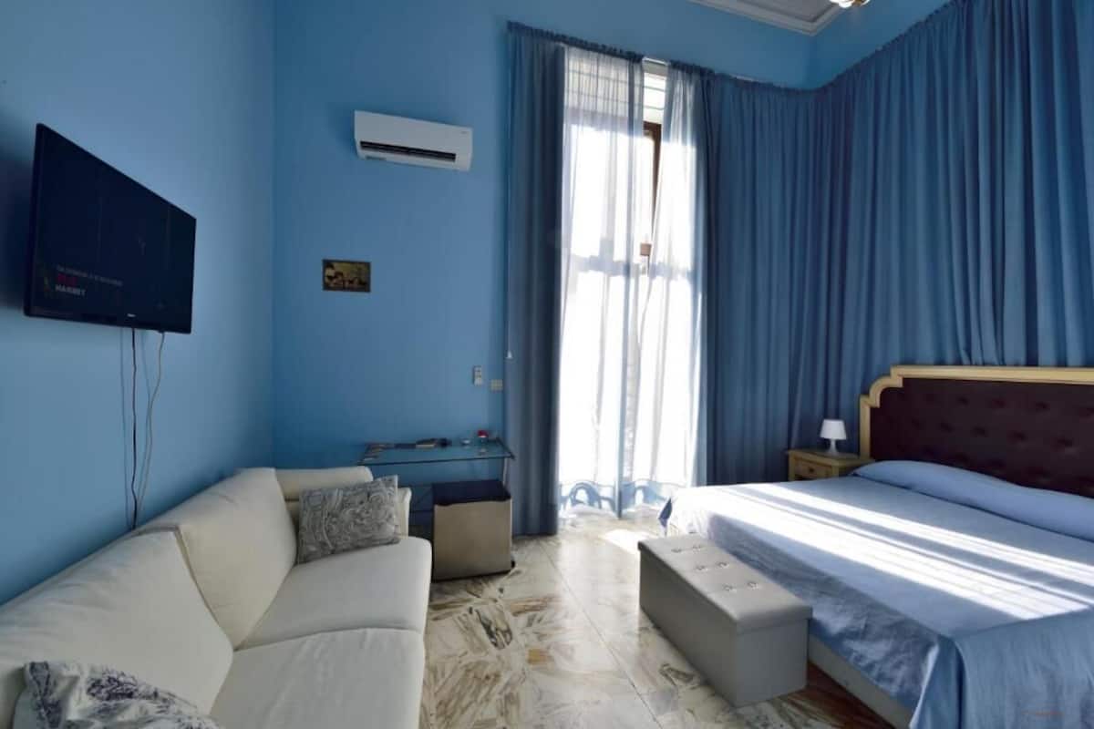 Una habitación de hotel con cama, sofá, escritorio y televisor.