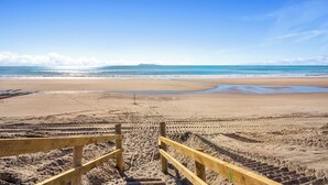 Ein Strand mit Holzstufen, die zum Ufer führen, feinem Sand und ruhigem Meer.